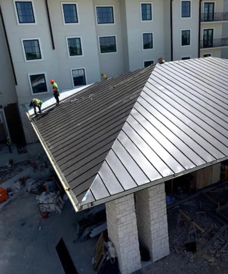 Crew installing standing seam metal roof panels on a commercial project in White
